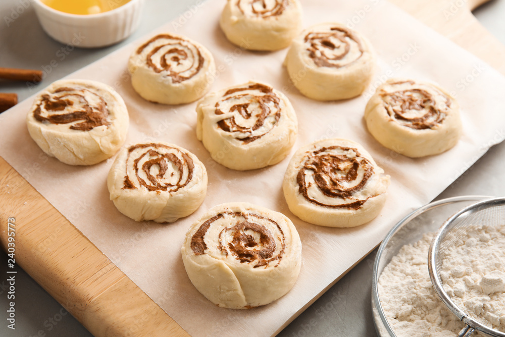 Wooden board with raw cinnamon rolls on table Wooden board with raw cinnamon rolls on table