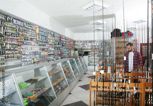 Customer choosing fishing equipment in sports shop