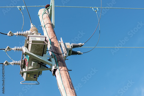 A close up of a British electric pole transformer taken against a bright blue sky