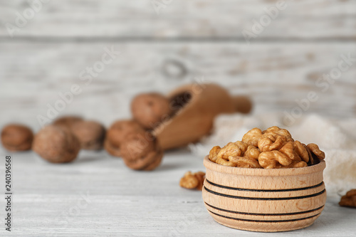 Bowl with tasty walnuts on wooden table. Space for text