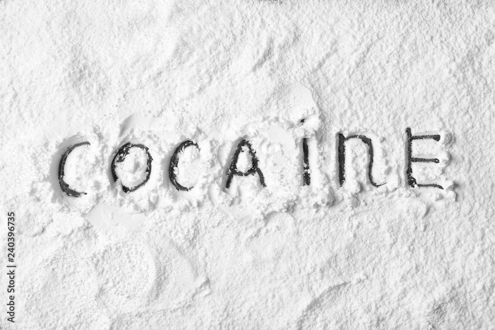 Word Cocaine written on white powder as background, top view Word Cocaine written on white powder as background, top view