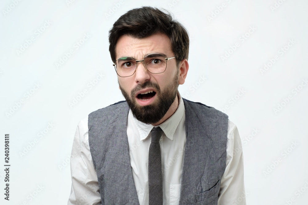 Suspicious bearded man looks doubtfully, being indecisive, makes grimace, tries to find solution. Facial expressions concept. Suspicious bearded man looks doubtfully, being indecisive, makes grimace, tries to find solution. Facial expressions concept.