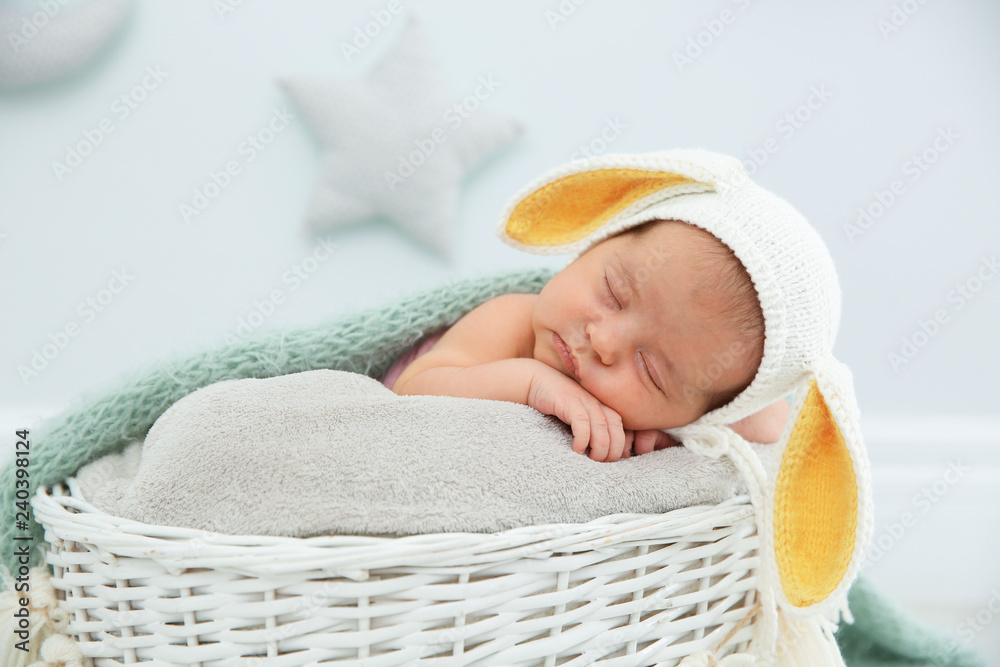 Obraz premium Adorable newborn child wearing bunny ears hat in baby nest indoors