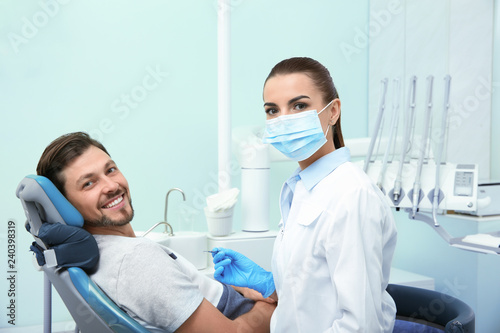 Professional dentist and happy patient in modern clinic