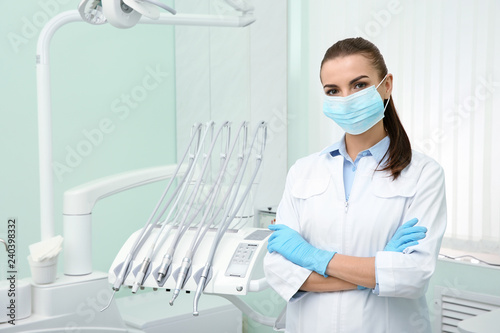 Young female dentist in white coat at workplace. Space for text