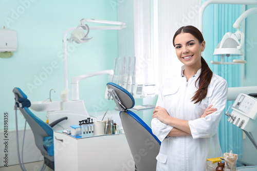 Young female dentist in white coat at workplace. Space for text photo