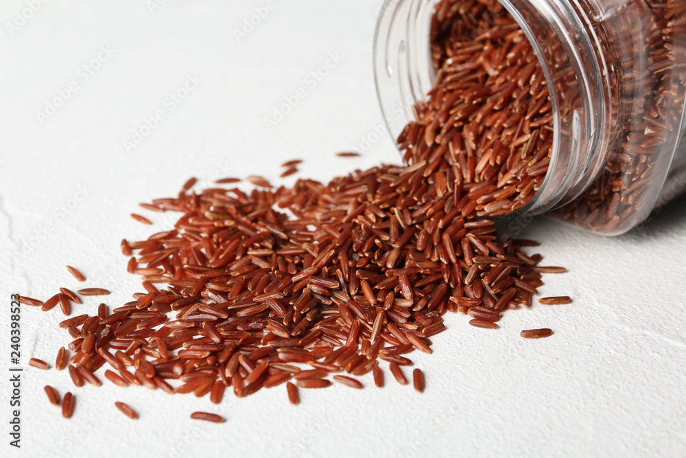 Fototapeta premium Pile of brown rice and jar on table, closeup