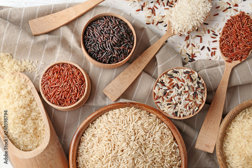 Flat lay composition with brown and other types of rice on wooden background