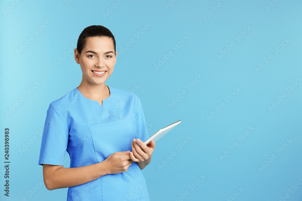 Portrait of young medical assistant with tablet on color background. Space for text Portrait of young medical assistant with tablet on color background. Space for text