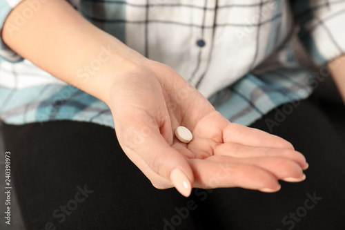 Woman holding pill in hand, closeup view