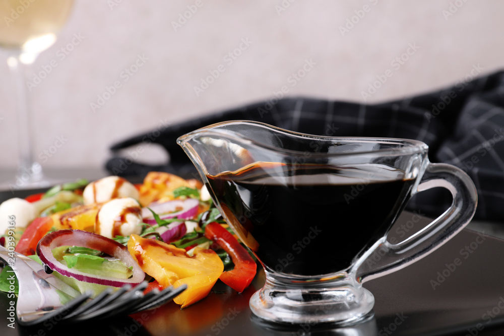 Gravy boat of balsamic vinegar on plate with vegetable salad, closeup Gravy boat of balsamic vinegar on plate with vegetable salad, closeup