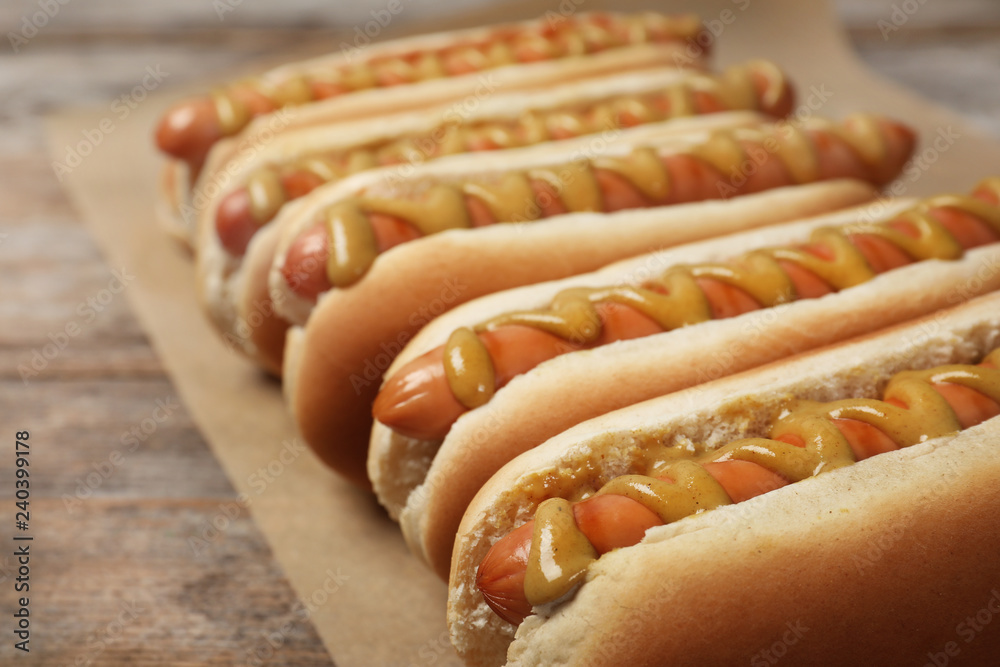 Hot dogs with mustard on wooden table, closeup - obrazy, fototapety, plakaty 