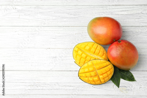 Flat lay composition with mango on white wooden background. Space for text