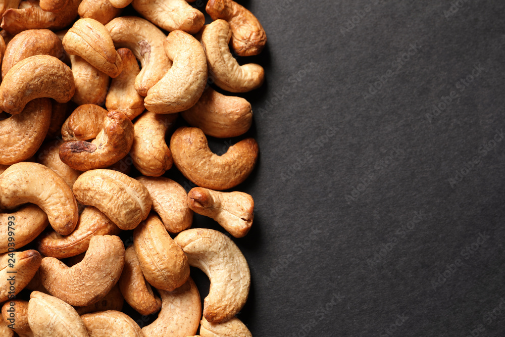 Fototapeta premium Tasty cashew nuts on black background, top view. Space for text