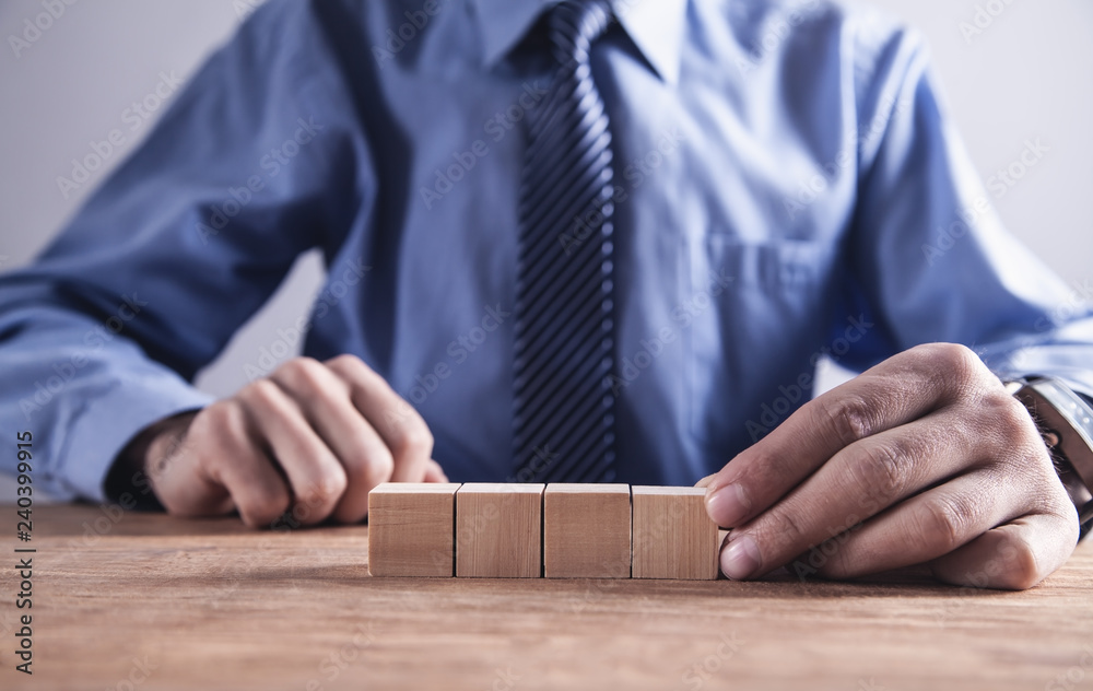 Businessman holding wooden cube on a wooden table. Businessman holding wooden cube on a wooden table.