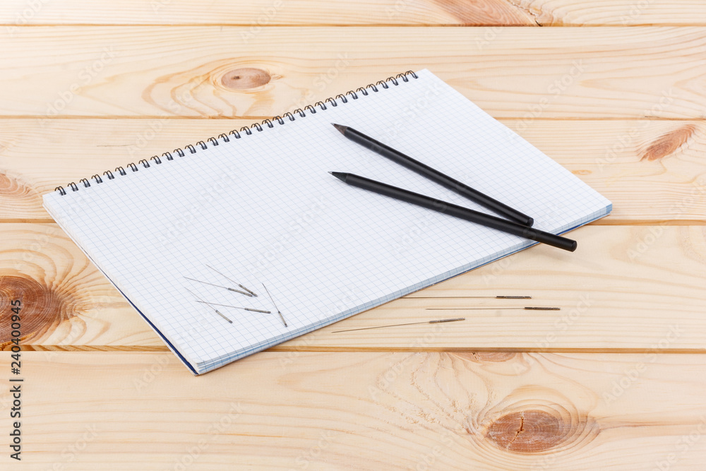 Silver needles for traditional Chinese medicine acupuncture lie on a note book, on a wooden table. Silver needles for traditional Chinese medicine acupuncture lie on a note book, on a wooden table.