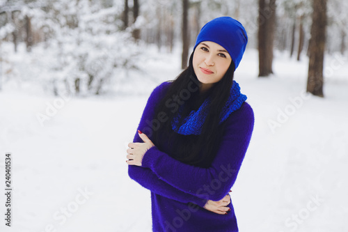 Young beautiful brunette girl in a sweater in the winter snowy forest