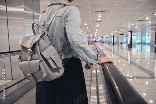 the girl is riding on the travolator at the airport with a laptop photo