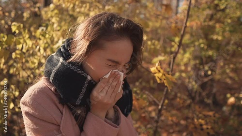 Sick girl sneezing outdoor.