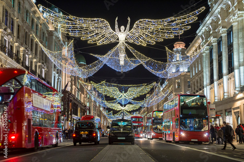 Red double-decker buses pass under twinkling Christmas lights along the upscale shopping district of Regent Street.