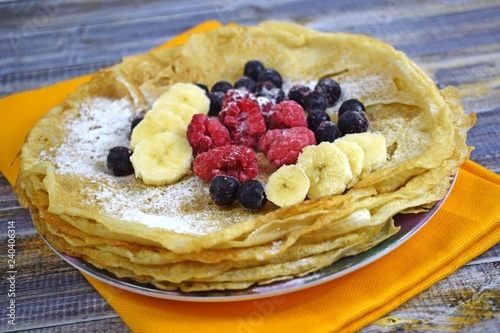 Delicious hot pancakes with fresh fruit on wooden background.