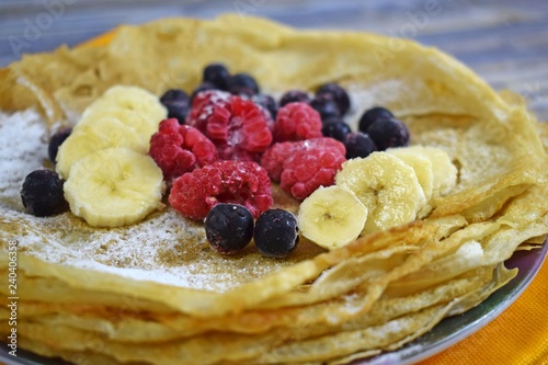 Delicious hot pancakes with fresh fruit on wooden background.