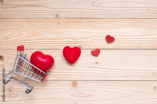 Top view couple red heart shape with mini shopping cart on wooden table. love, shopping and Valentine Day Concept