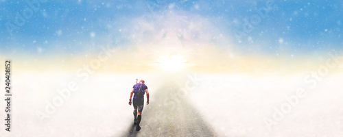 Man walking on a road into the sunset in winter 