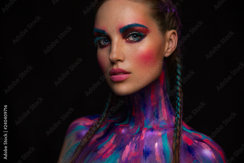 Fashion portrait of beautiful young woman with bright pink and blue colors, art make-up, face art on dark background Fashion portrait of beautiful young woman with bright pink and blue colors, art make-up, face art on dark background