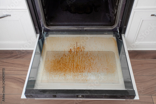 Dirty oven door in the kitchen. Cleaning and tidying.