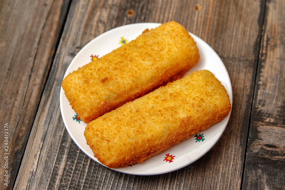 Crispy breaded fried hake fish fillet on old wooden table Crispy breaded fried hake fish fillet on old wooden table