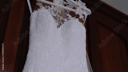 Detail of lace wedding dress hanging in the room.