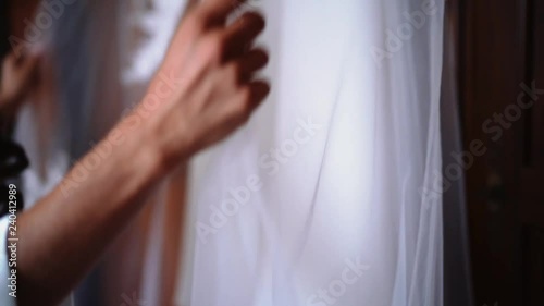 Detail of lace wedding dress hanging in the room.