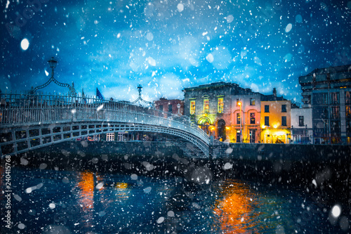 Evening view of Dublin Ireland at the Ha'Penny Bridge of the River Liffey with snowflakes falling during winter snow storm photo
