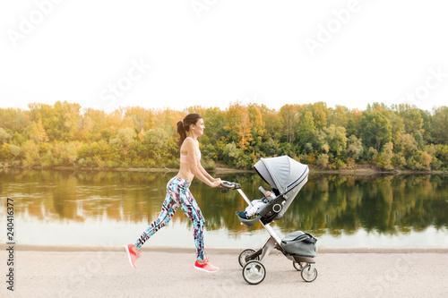 Active mother jogging. Jogging or power walking woman with pram at sunset. Mother with child in stroller running