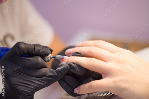 Hardware Manicure using electric device machine. procedure for the preparation of nails before applying nail polish. Hands of Manicurist in black gloves and Nails of Client. Woman In Beauty Salon