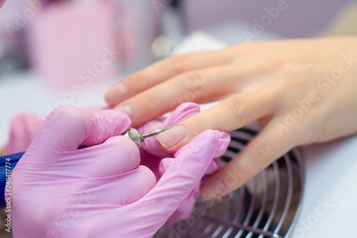 Hardware Manicure using electric device machine. procedure for the preparation of nails before applying nail polish. Hands of Manicurist in pink gloves and Nails of Client. Woman In Beauty Salon