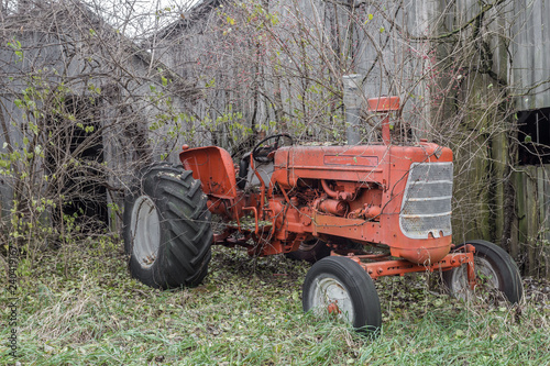 Vintage tractor left to rot in front of abandoned barn