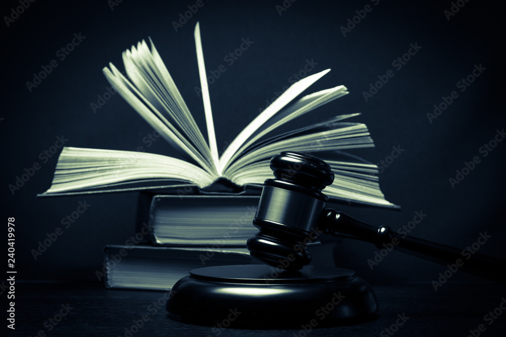 Judge gavel beside pile of books on wooden background Judge gavel beside pile of books on wooden background