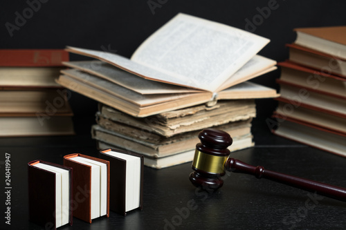 Judge gavel beside pile of books on wooden background