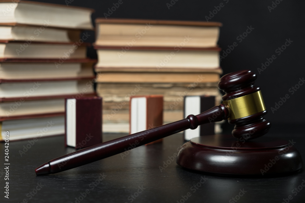 Judge gavel beside pile of books on wooden background Judge gavel beside pile of books on wooden background