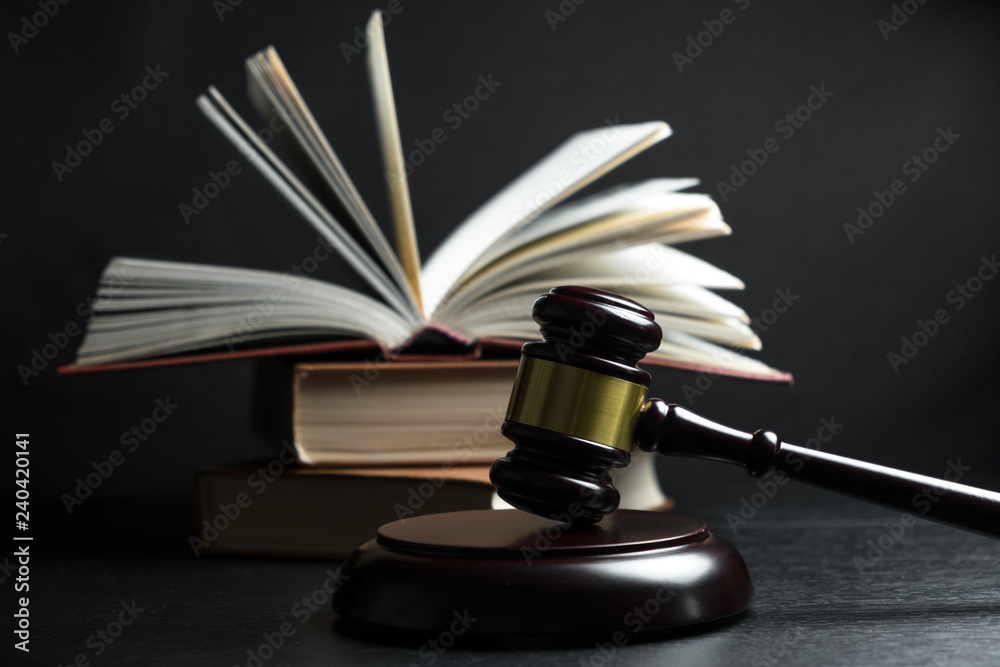Judge gavel beside pile of books on wooden background