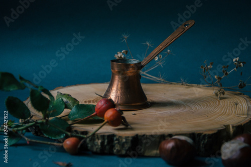 Old turkish coffee maker on a wooden board with dried rose