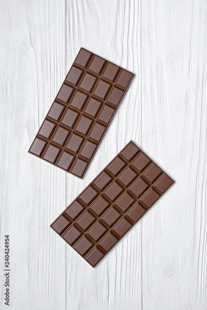 Top view on tasty chocolate bars on white wooden background Top view on tasty chocolate bars on white wooden background
