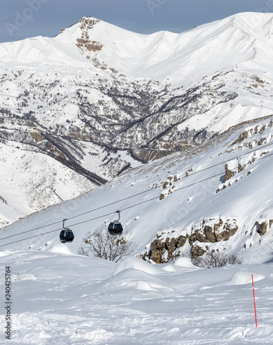 Snow-covered off-piste ski slope in snowy mountains and gondola lift photo