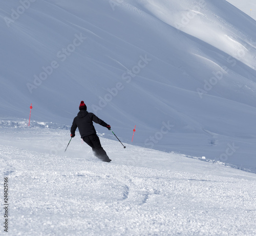 Skier downhill on prepared snowy ski slope at winter day photo