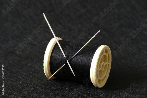 sewing needle and rope reel, on black background,