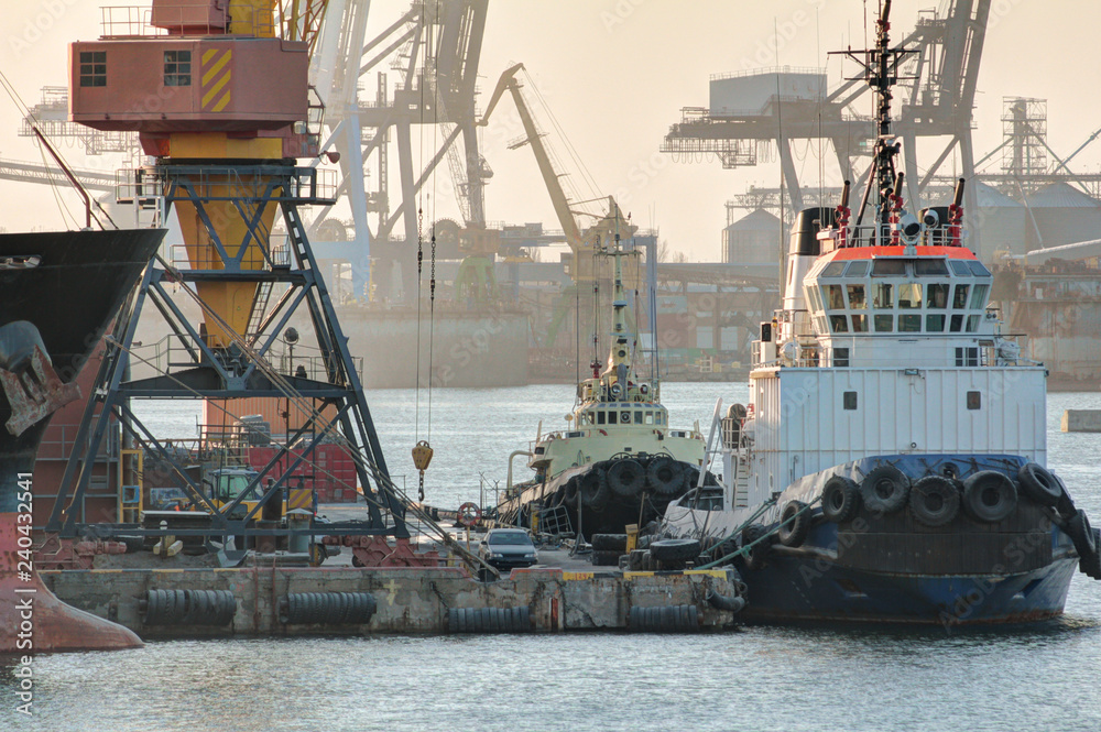 The tugboat is at the pier in the port. Wiew of the evening port. The tugboat is at the pier in the port. Wiew of the evening port.