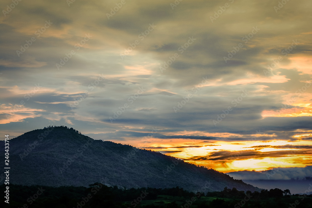 Fototapeta premium Dramatic of sunset after the mountain with rain clouds golden