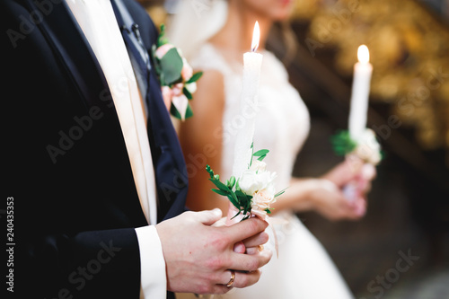 Bride and groom holding candles in church photo